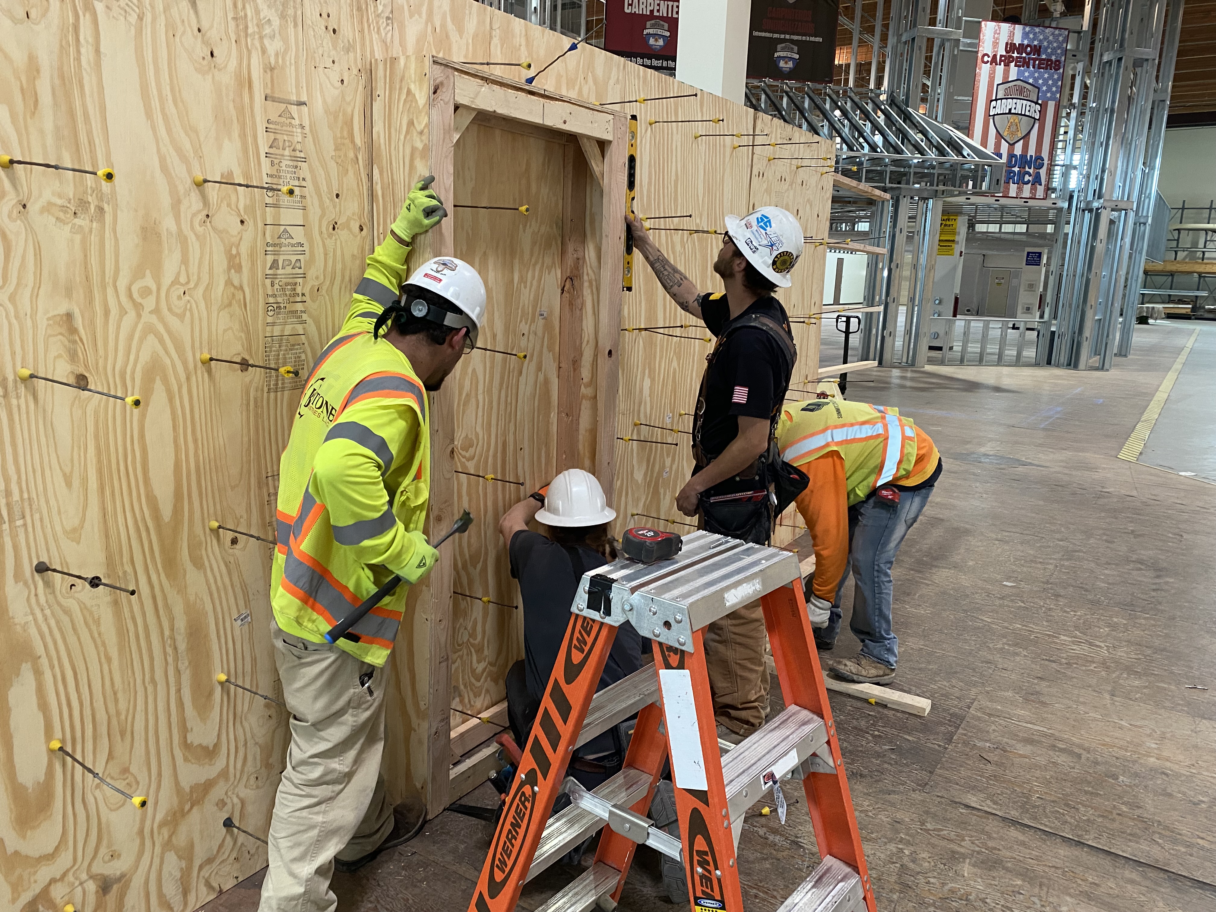 Carpenters installing doorframe Four carpenters install a doorframe on a plywood structure.